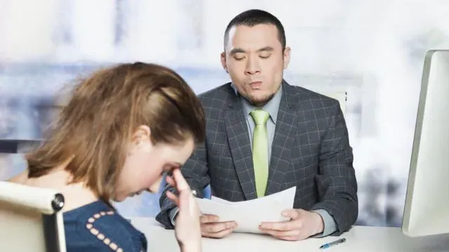 Man reviewing a document; woman with head in hands